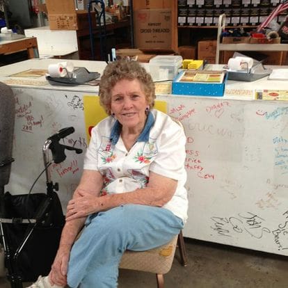 Smiling elderly woman sitting at a counter.