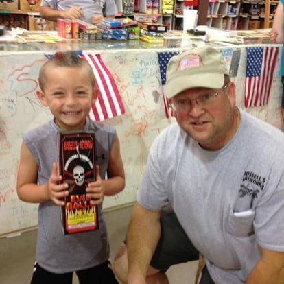 Boy holding fireworks with a man.