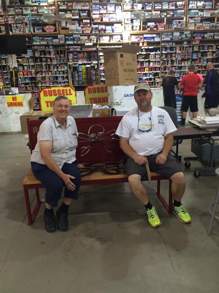 Couple sitting on bench in fireworks store.